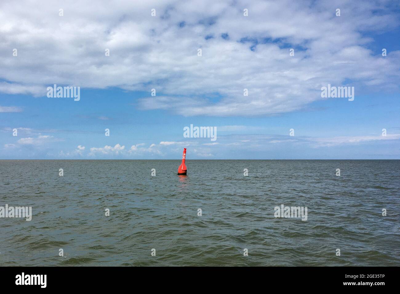 A Red Buoy on the North Sea in the East Frisian Wadden Sea in front of Juist Island, Germany. Stock Photo