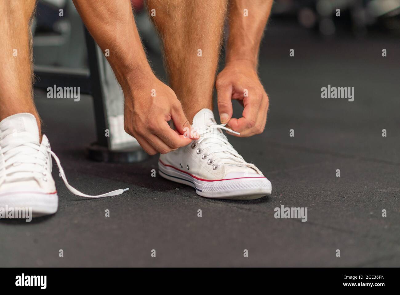 View of Sport man tying his shoelaces before a workout in a gym.Cropped image ...