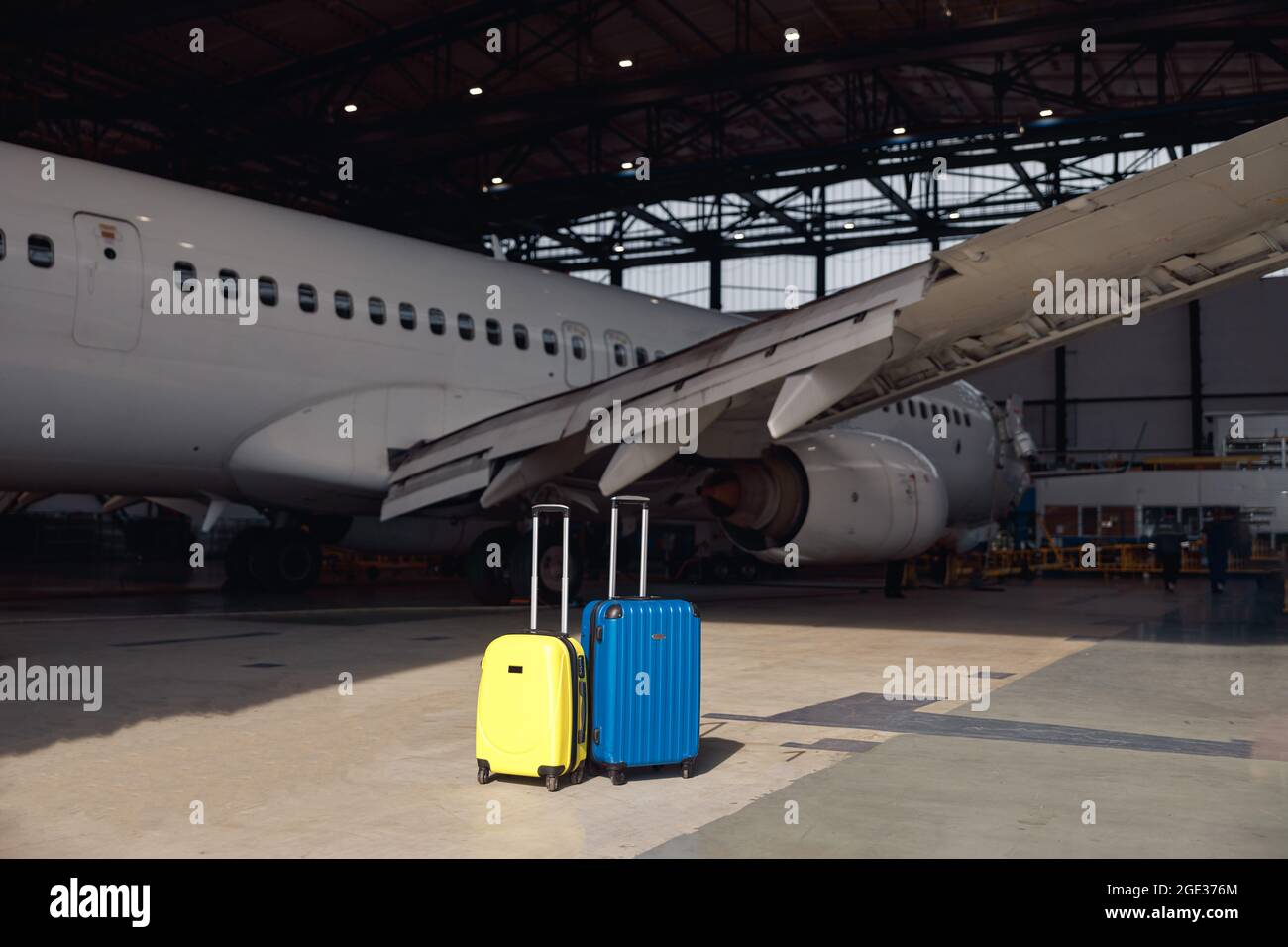 Two colorful suitcases of air stewardesses in empty airport hangar on a sunny day Stock Photo