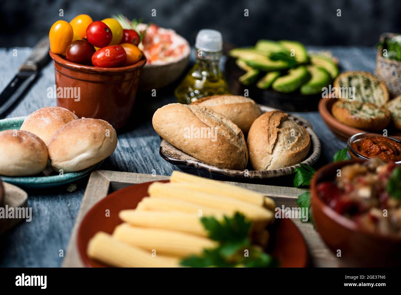 closeup of some different ingredients on a table to prepare vegan sandwiches or appetizers, such as different bread buns, cooked baby corns, cherry to Stock Photo