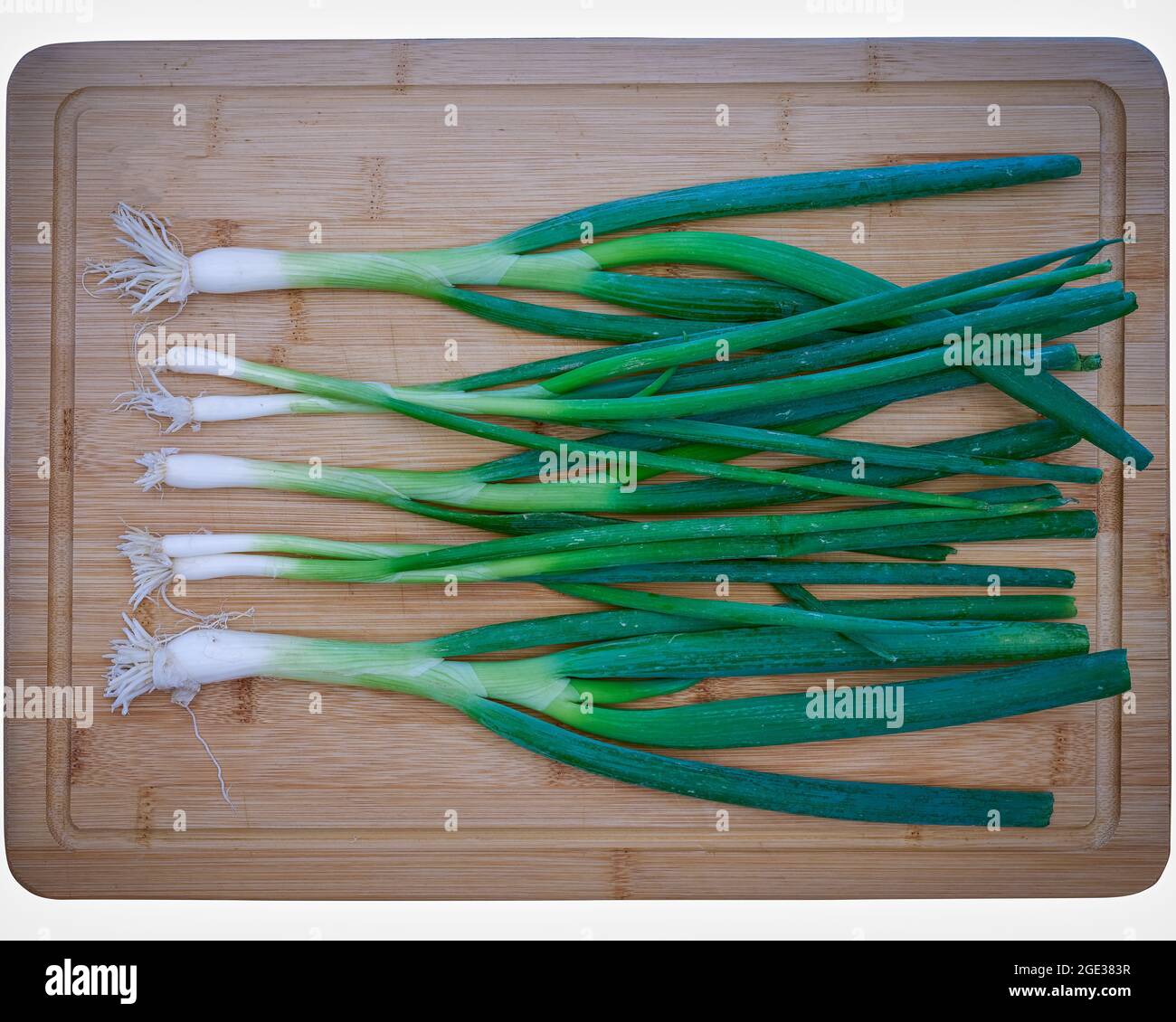 Food, Deutschland, Frühlingszwiebeln liegen auf einem Schneidebrett aus Bambus Stock Photo