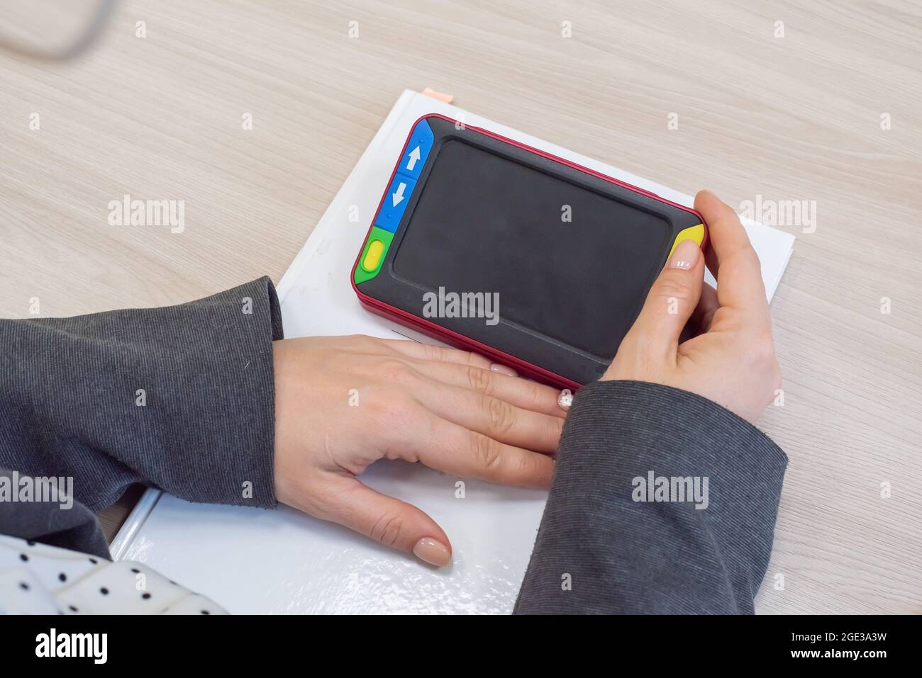 The woman is holding a reading device for the visually impaired