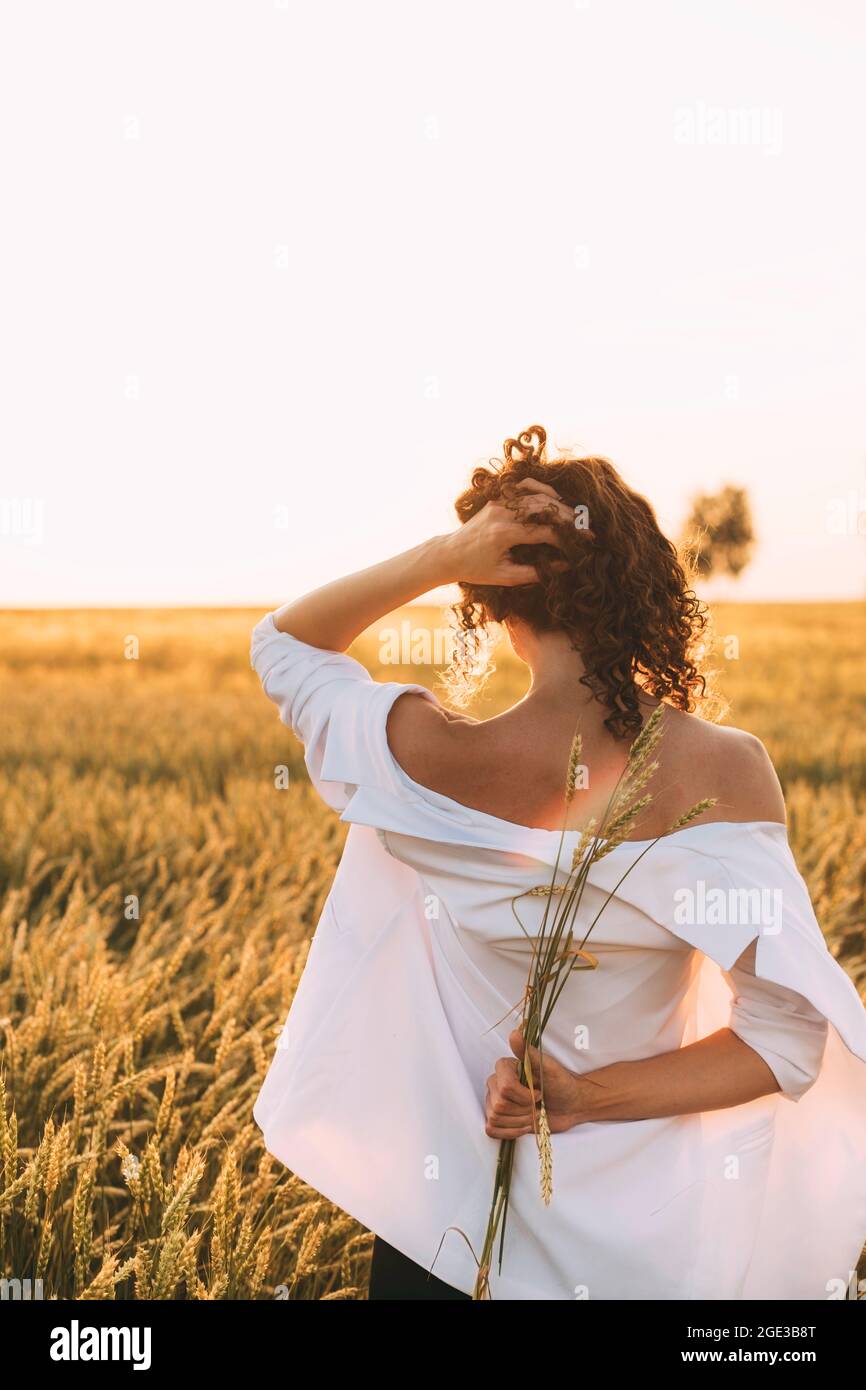 Happy woman enjoying the life in the sunny field. Nature beauty, and field with golden wheat. Outdoor lifestyle. Freedom concept. Woman in summer fiel Stock Photo