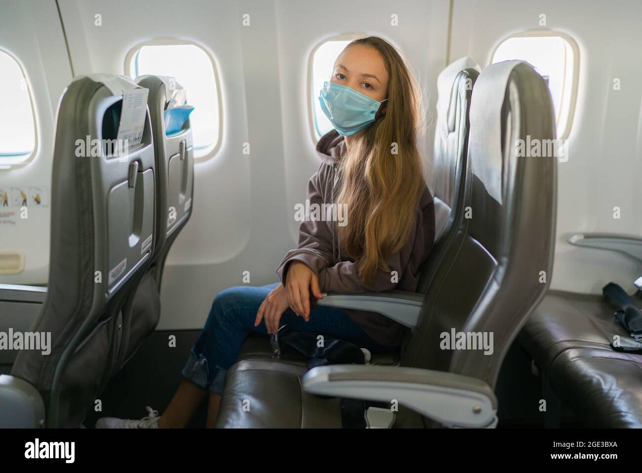 Pretty blonde woman wearing face mask during flight on plane Stock