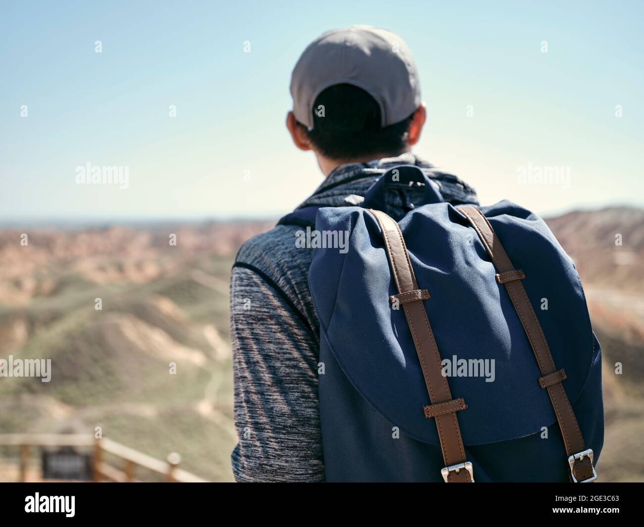 rear view of an asian man male tourist backpacker looking at the yardang landforms in national geological park Stock Photo