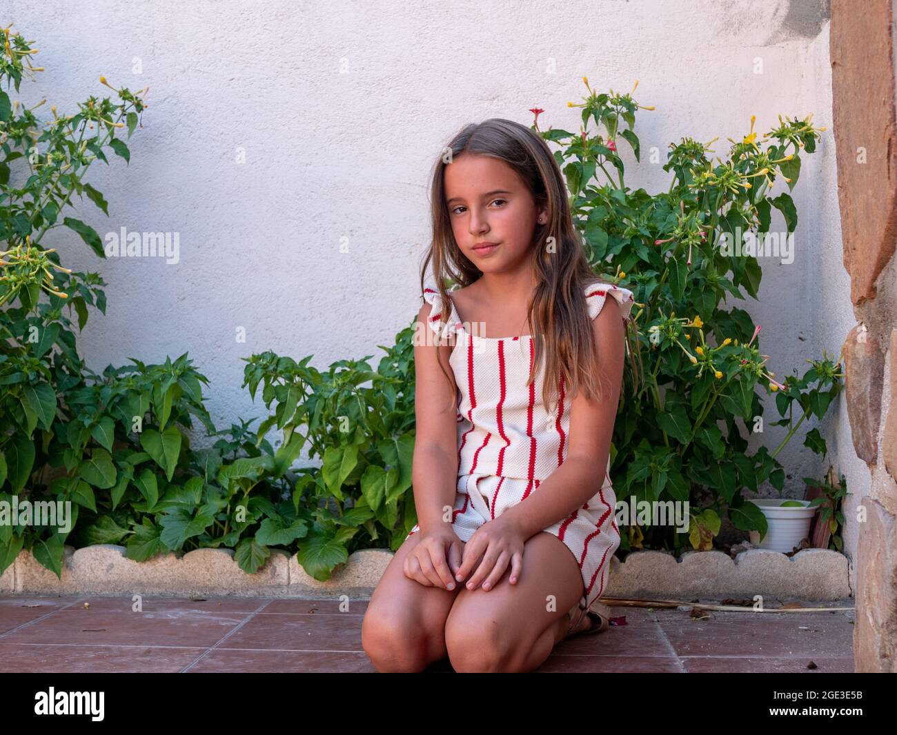 Cute Caucasian girl sitting on the floor in a garden Stock Photo - Alamy