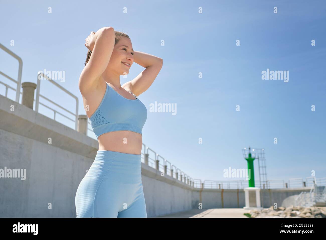 Side view of young sincere female athlete in sportswear with hands behind head looking forward during break from workout Stock Photo