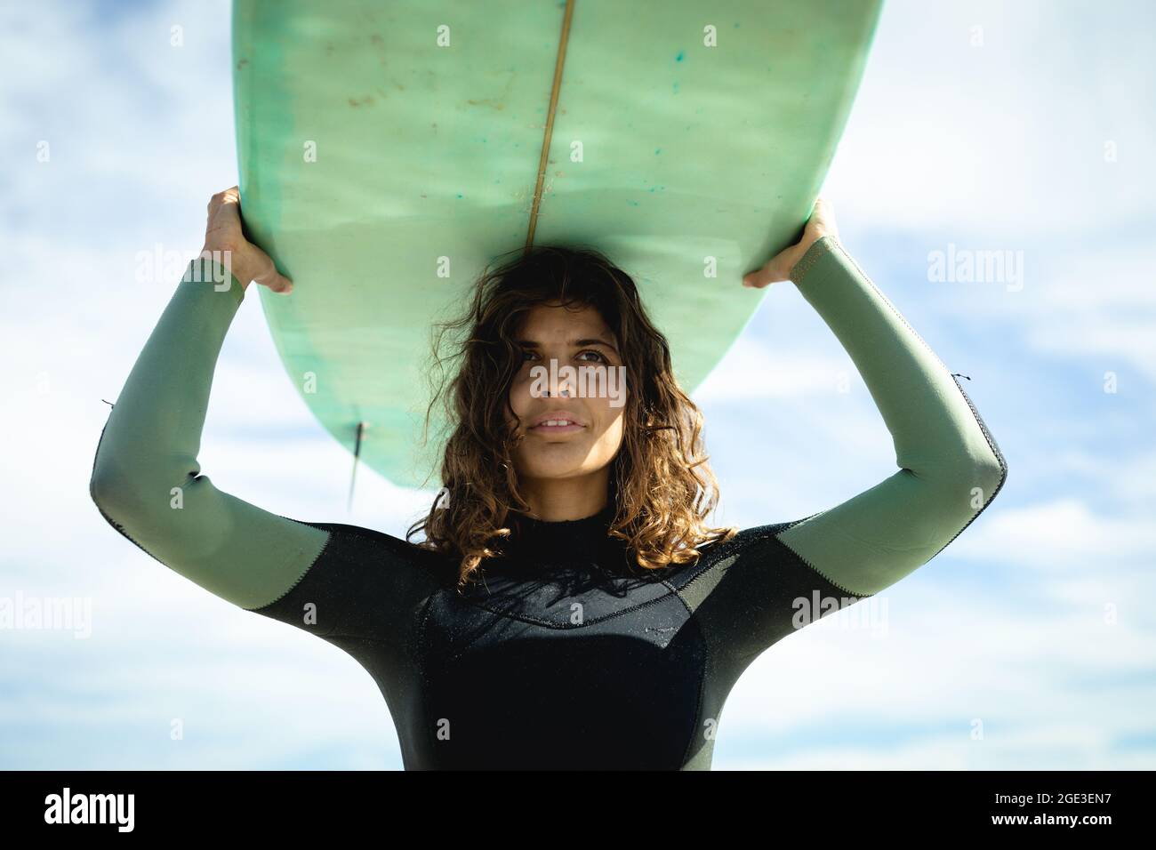Mixed race woman holding surfboard on sunny day at beach Stock Photo