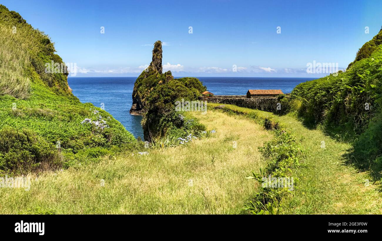 Picturesque panorama with a small picnic area by the sea with rocks and a green meadow Stock Photo