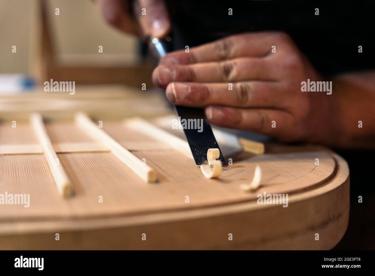 Unrecognized craftsman creating a guitar and using tools in a traditional workshop. Stock Photo