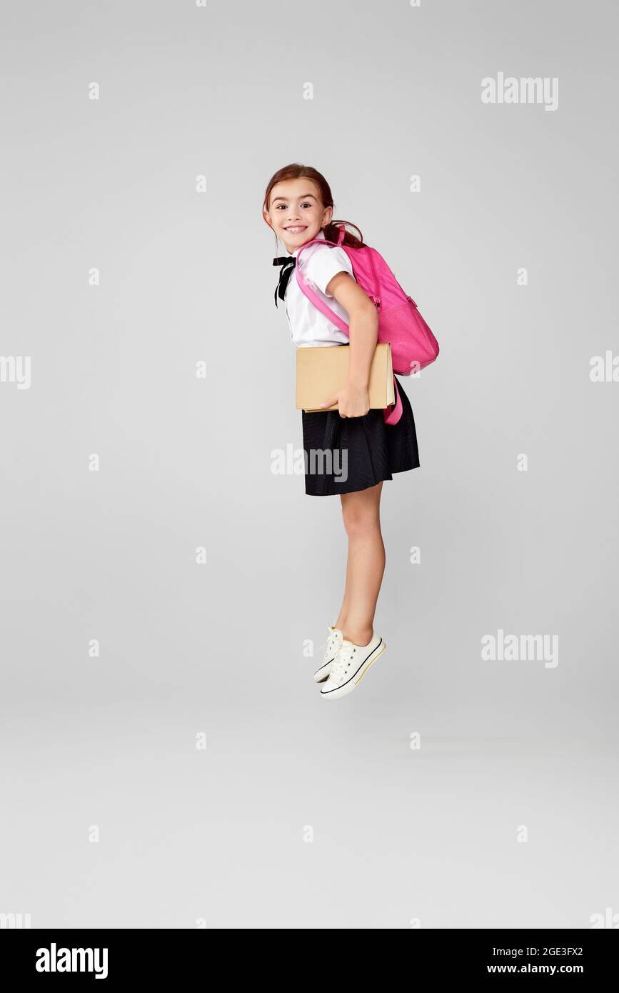cute happy schoolgirl jumping up with backpack Stock Photo