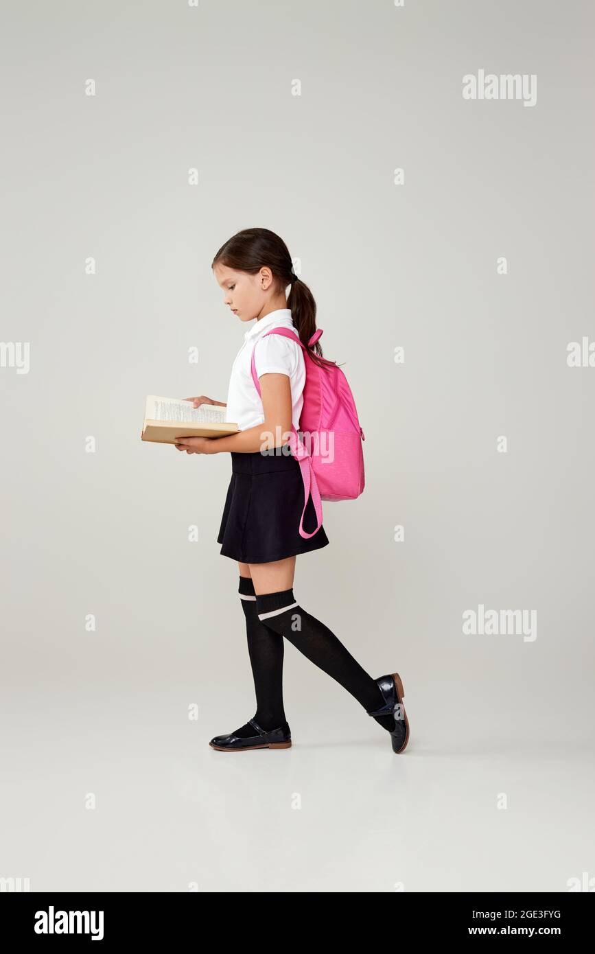 cute schoolgirl with backpack and book full length Stock Photo - Alamy