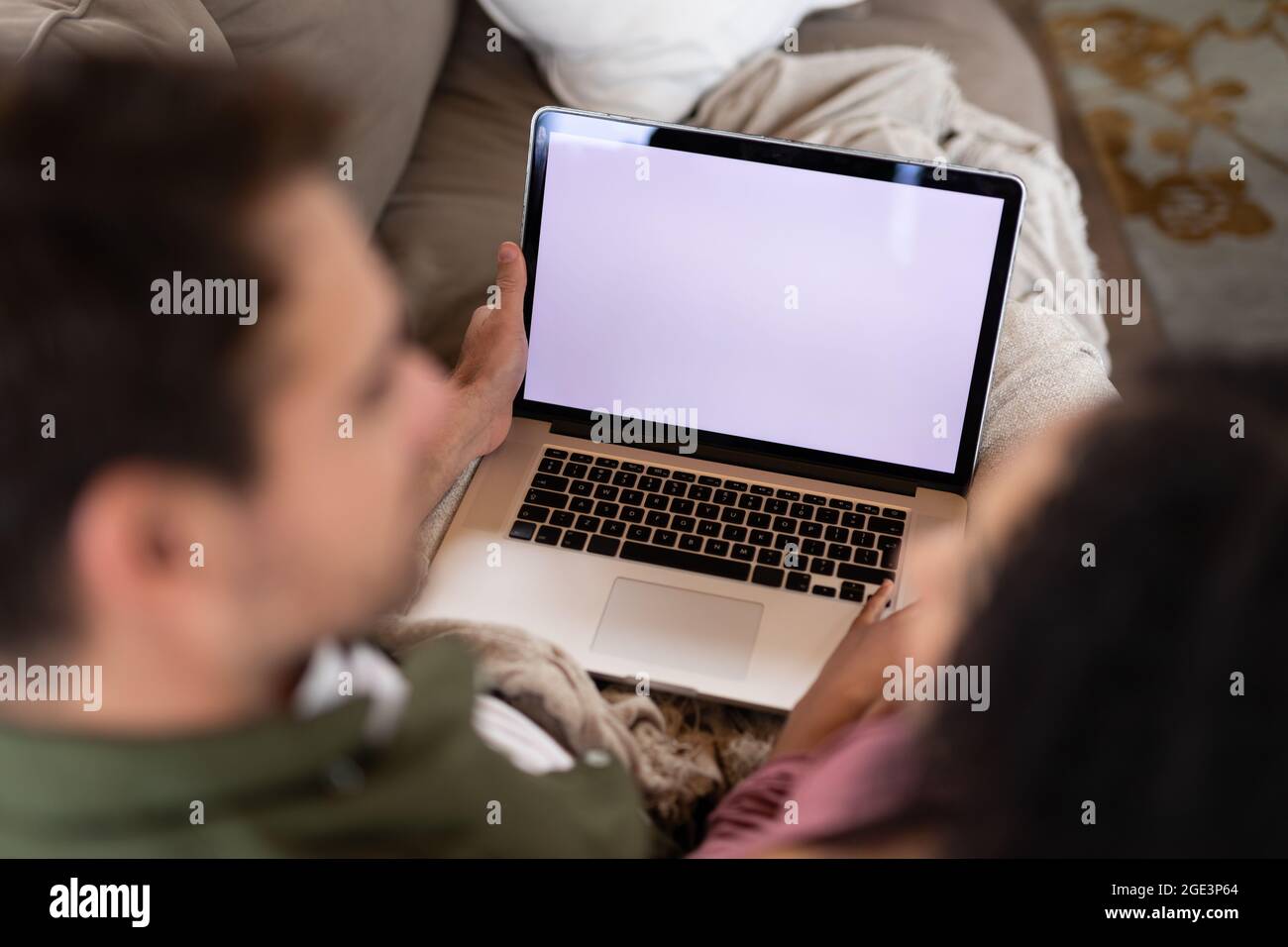Happy diverse couple sitting on sofa in living room using laptop Stock ...