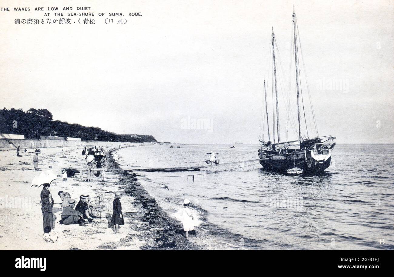 Old Japanese postcard, black and white, circa 1910, of a Japanese junk being unloaded, moored just off the seashore at the beach at Suma, near Kobe. Stock Photo