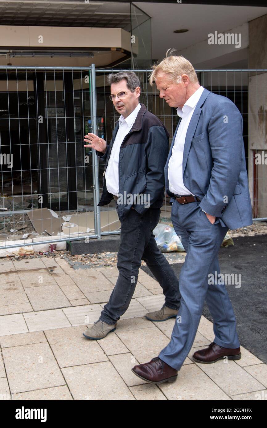 Stolberg, Germany. 16th Aug, 2021. Reiner Hoffmann (r), Chairman of the German Trade Union Confederation (DGB), and Ralf Woelk, Regional Director of the DGB NRW-South-West, walk past a destroyed shop. As part of his summer trip, Hoffmann took a look at the storm damage and spoke to works councils at affected companies. Credit: Marius Becker/dpa/Alamy Live News Stock Photo
