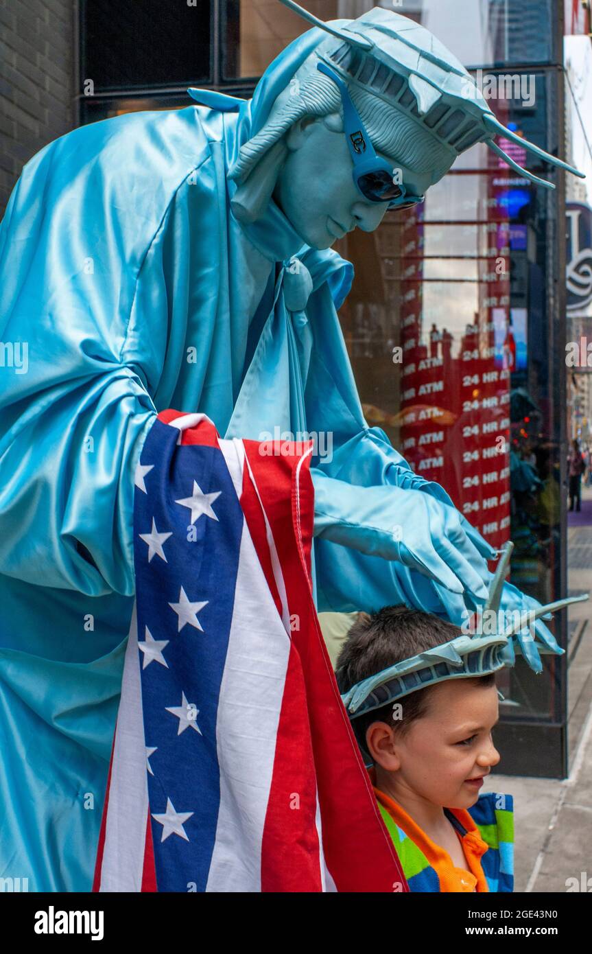 A human statue dressed in Statue of Liberty is pictured with a child near Times Square. If we want good photos of Times Square, we can go to the bar o Stock Photo