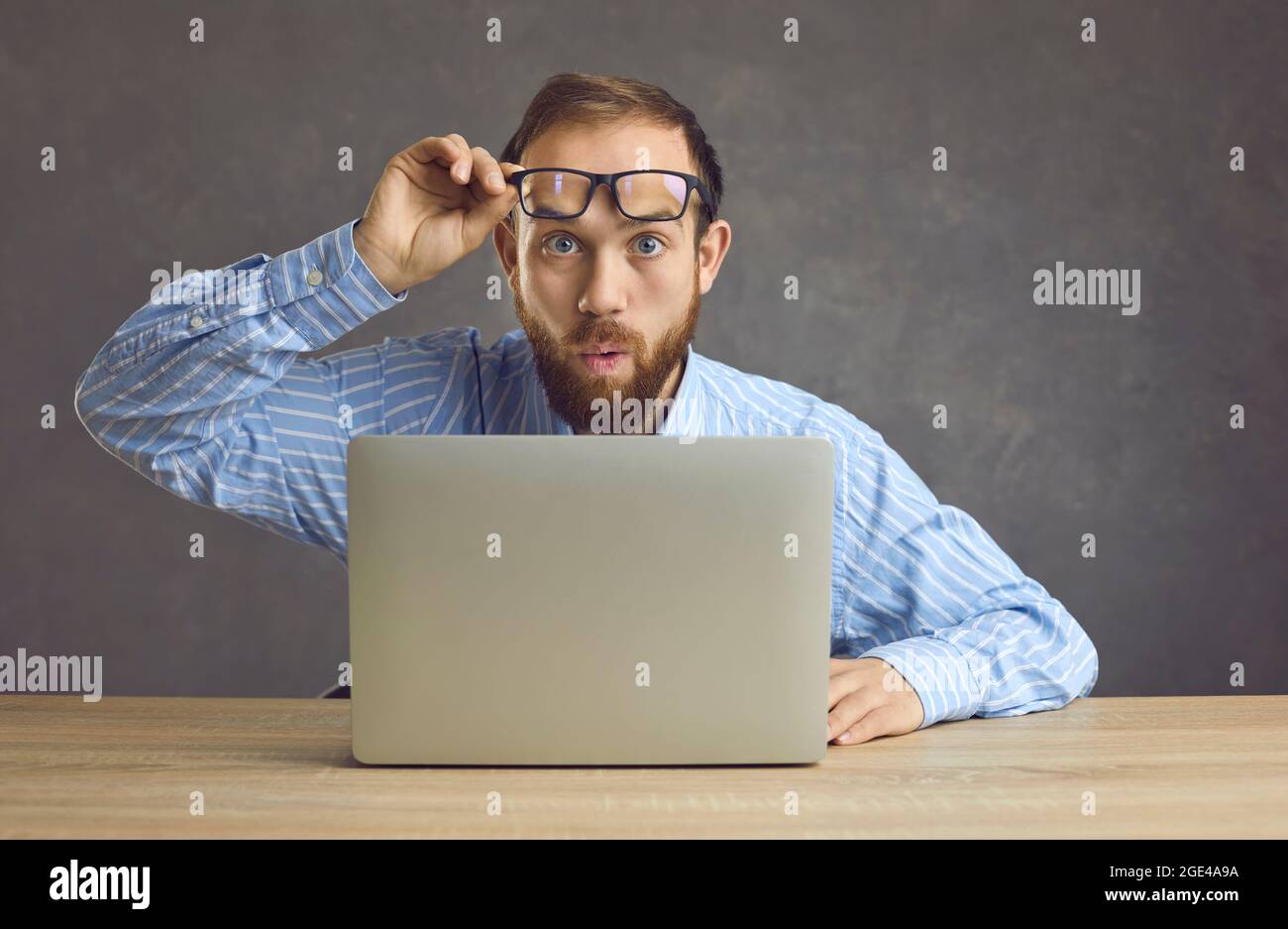 Surprised worker takes off glasses and looks at something shocking happening in office Stock Photo