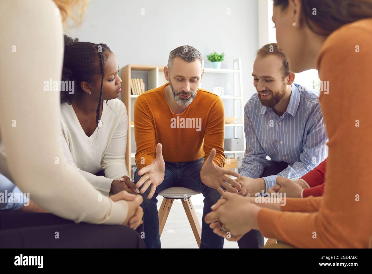 Professional therapist talking to diverse patients during a group therapy session Stock Photo