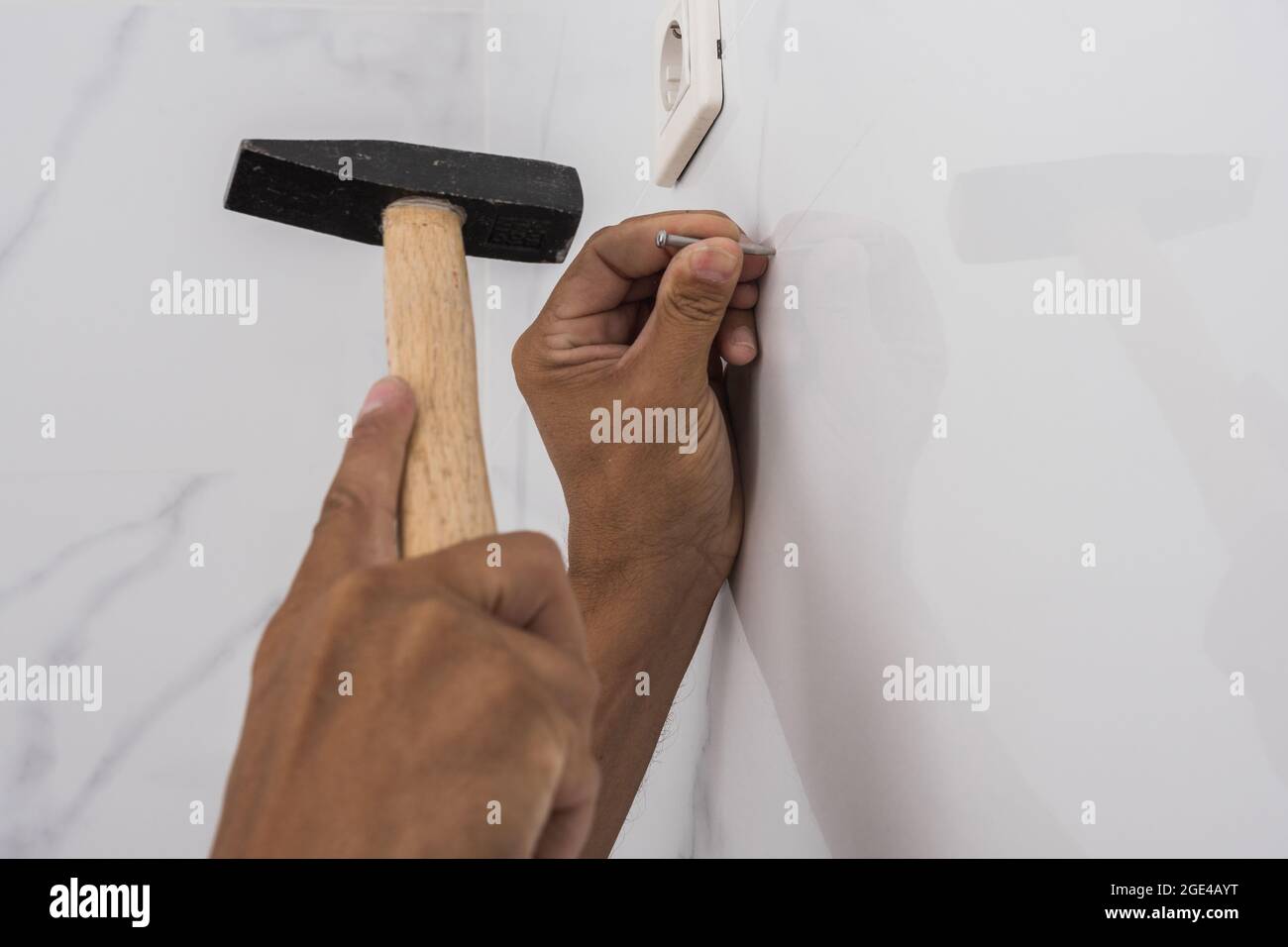 Man's hands hammering a nail into a wall Stock Photo Alamy