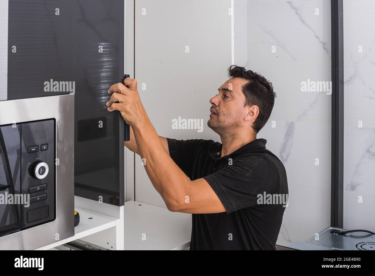 Adult man assembling a kitchen in a house Stock Photo