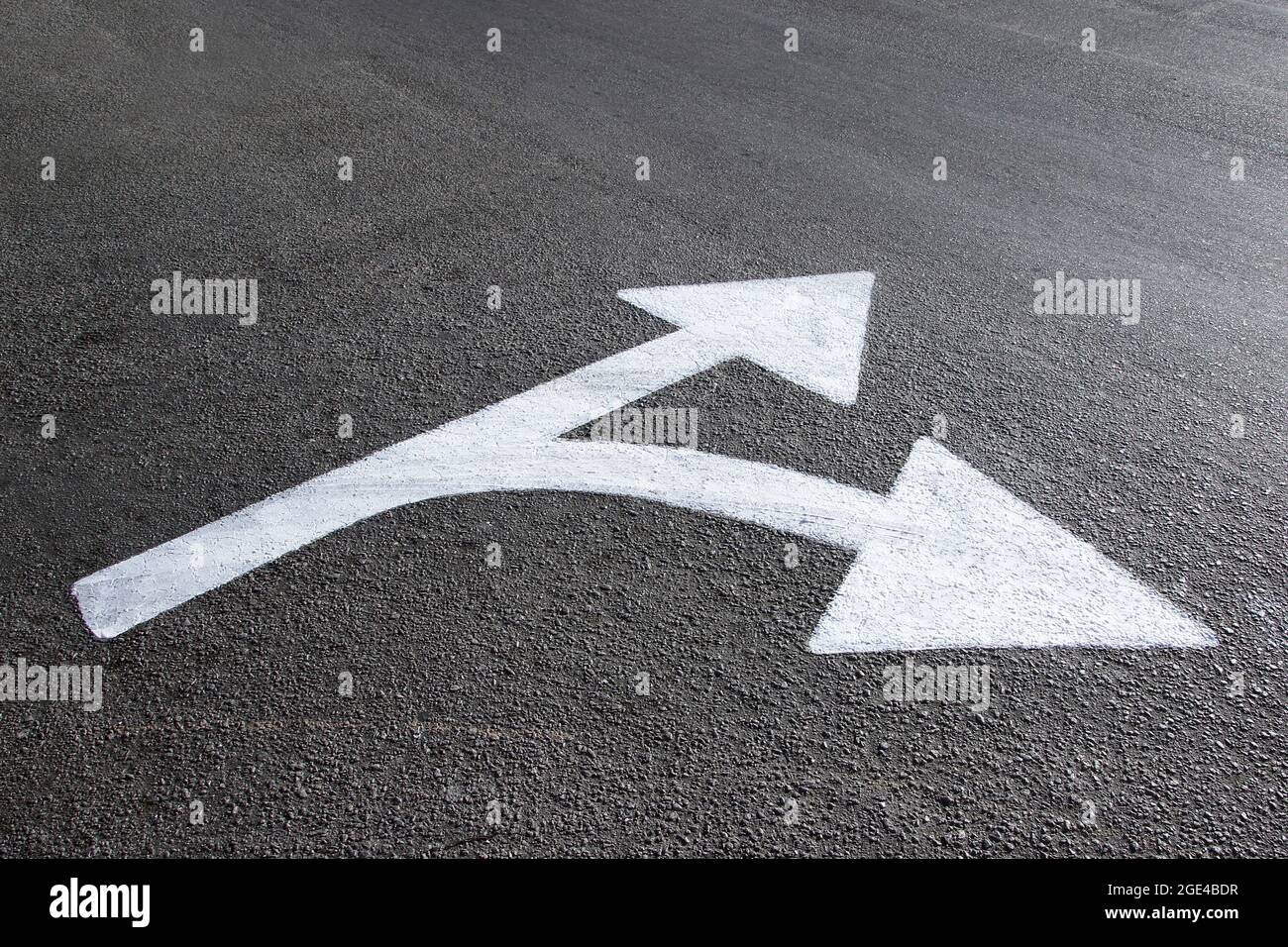 white directional arrow drawn on the asphalt ground concept of paths and directions Stock