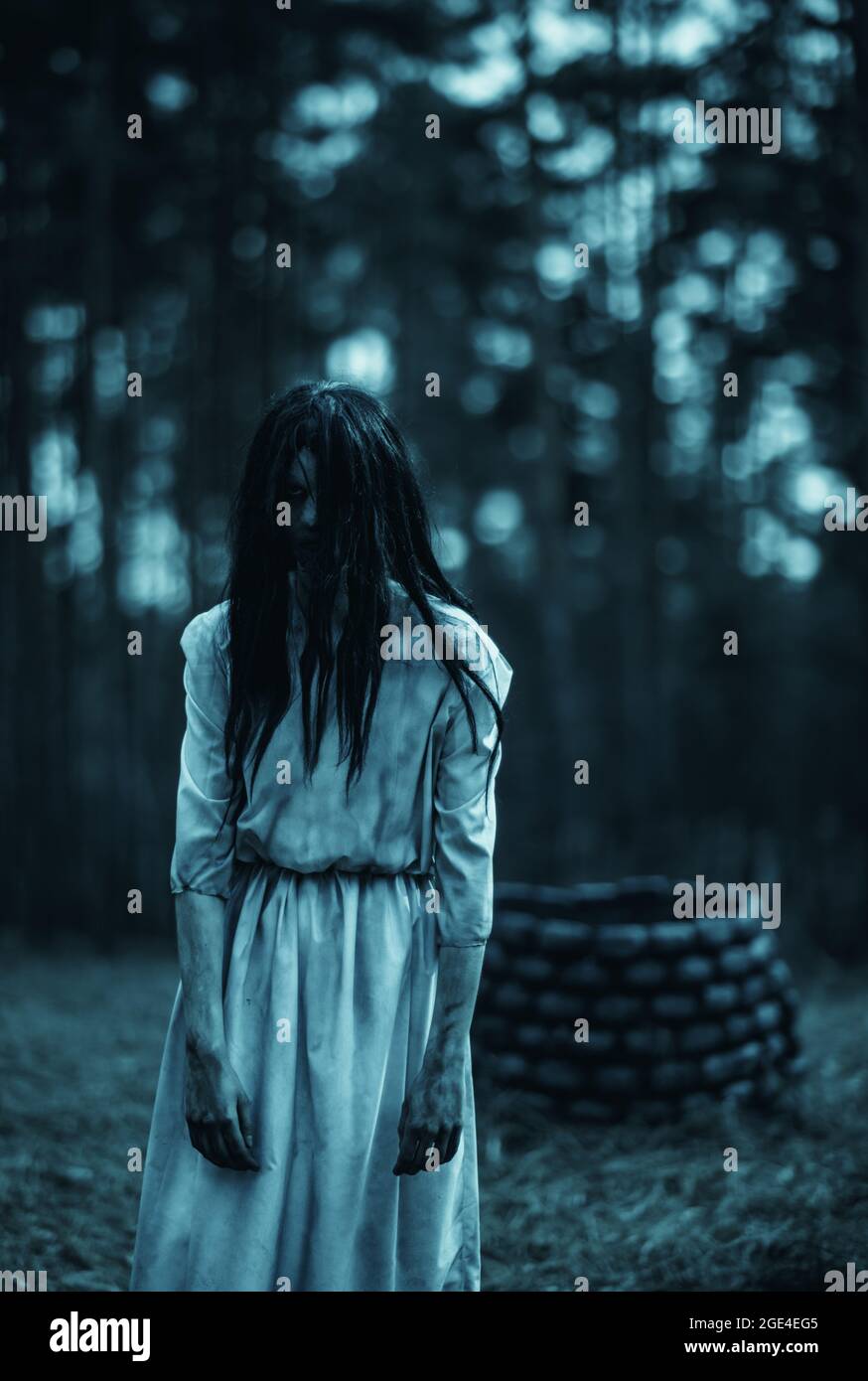 Girl with long black hair in image of scary ghost zombie walks among dark  forest against background of stone well Stock Photo - Alamy