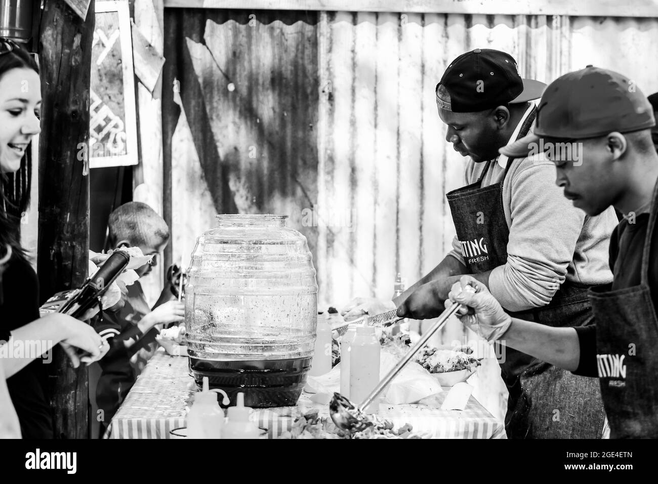 JOHANNESBURG, SOUTH AFRICA - Jan 05, 2021: A grayscale African male vendor selling take-out food at an outdoor stall at farmer's market Stock Photo