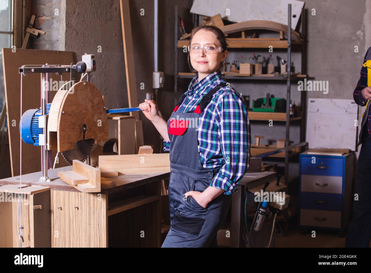 Female employee of woodworking plant operating circular saw Stock Photo