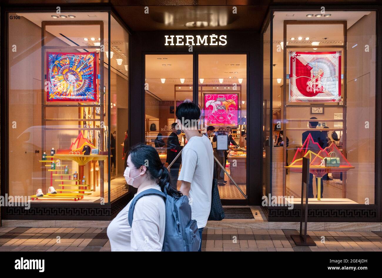 Hong Kong, China. 15th Aug, 2021. A couple walks past the French high  fashion luxury clothing manufacturer Hermes store seen in Hong Kong. (Photo  by Budrul Chukrut/SOPA Images/Sipa USA) Credit: Sipa USA/Alamy
