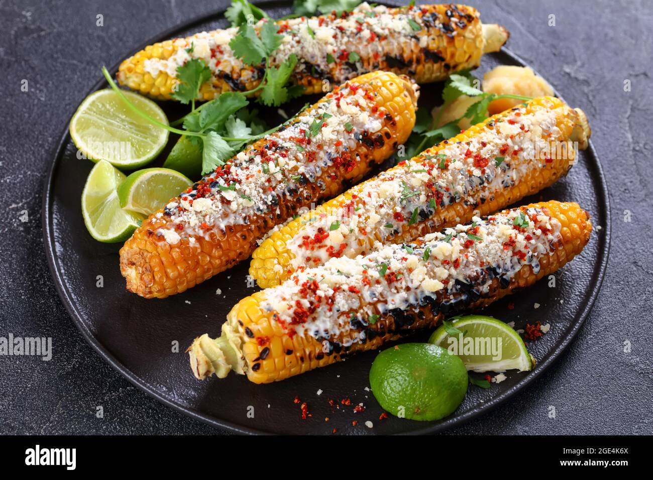 Elote, Grilled Mexican Street Corn, charred cobs are slathered in sour  cream based sauce, seasoned with chili powder and sprinkled with cheese,  cilant Stock Photo - Alamy