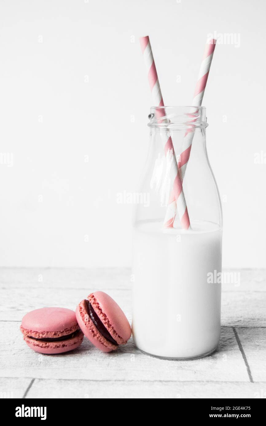 Small glass milk bottle with pink candy stripe paper straws and pink  macarons Stock Photo - Alamy