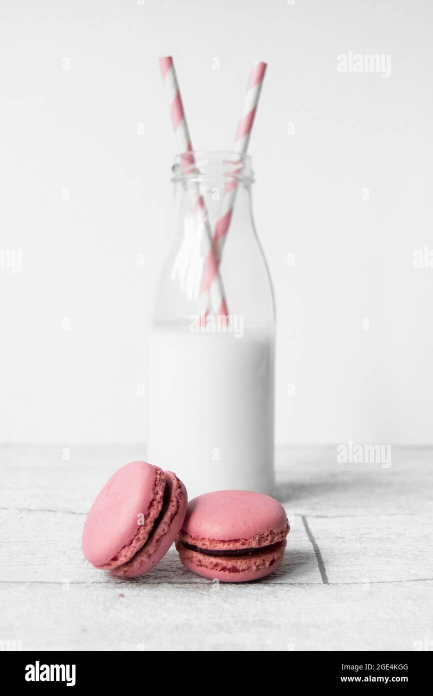 Small glass milk bottle with pink candy stripe paper straws and pink  macarons Stock Photo - Alamy