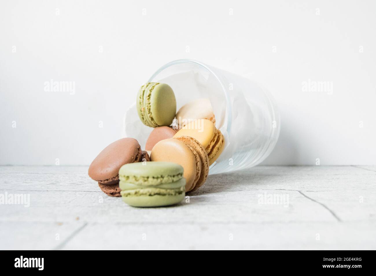Glass jar of pastel coloured macarons on a wood table top Stock Photo