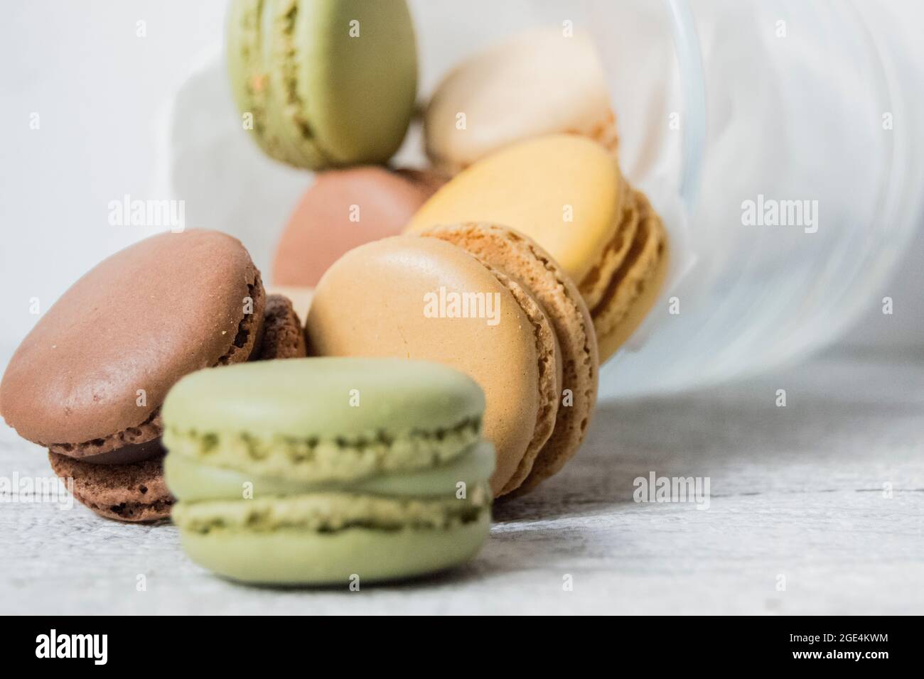 Glass jar of pastel coloured macarons on a wood table top Stock Photo