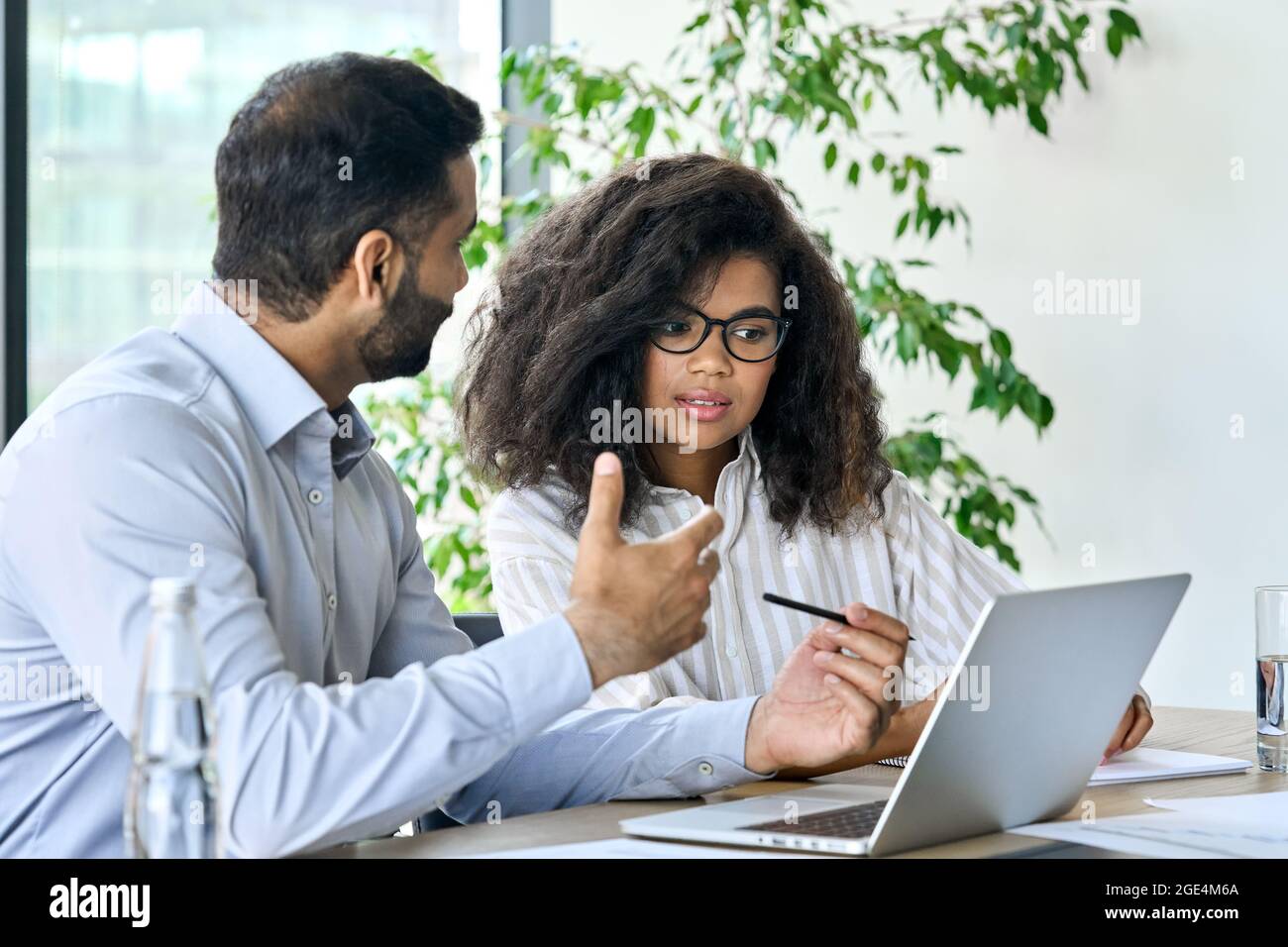 Indian ceo businessman banker talking to female client using laptop at meeting. Stock Photo