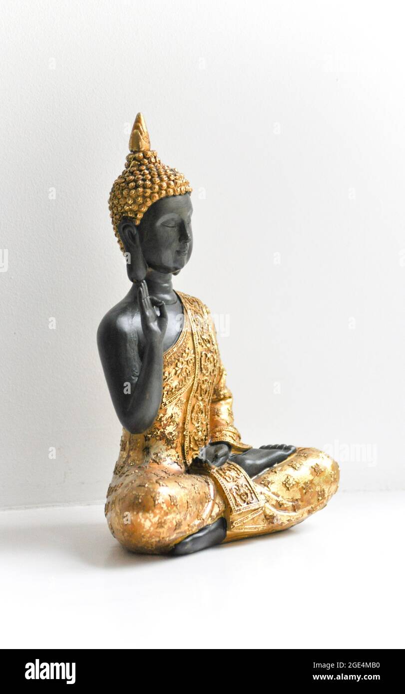 A golden Buddha statue set centrally in the image against a white background. Stock Photo