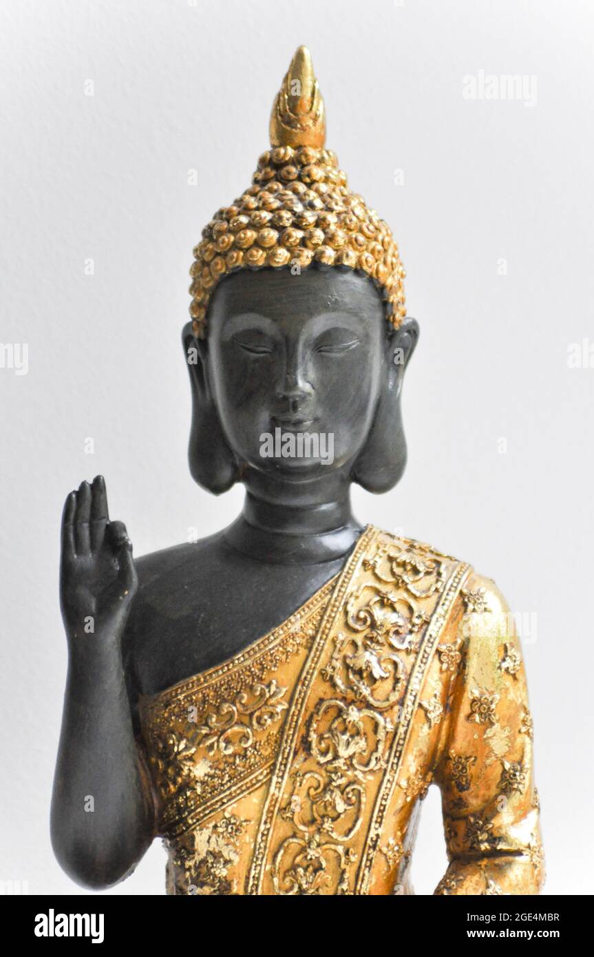 Upper body and face image of a golden Buddha statue set against a white background Stock Photo