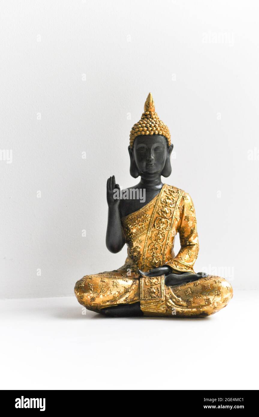 Golden Buddha statue set to the right of the image against a white background Stock Photo