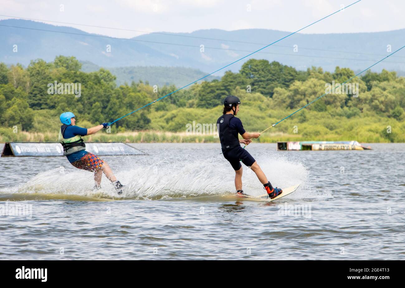 STRAZ p.R., CZECH REPUBLIC, JULY 13 2021, A young mens ride on surfboard. A group of surfer is pulled on a water towage on the lake. Stock Photo