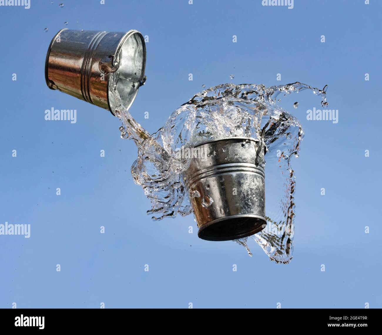 A pouring water from bucket to bucket, on a background of blue sky