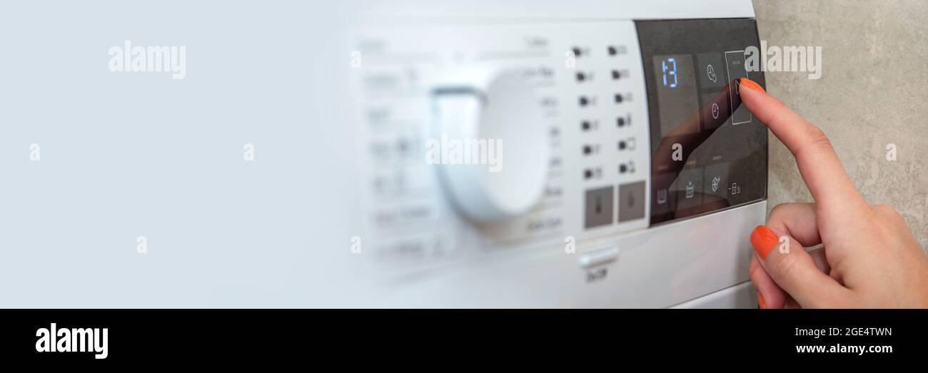 Washing machine. The hand turns on the washing machine or the choice of the washing program. Washing clothes. Banner for website or print with copy Stock Photo