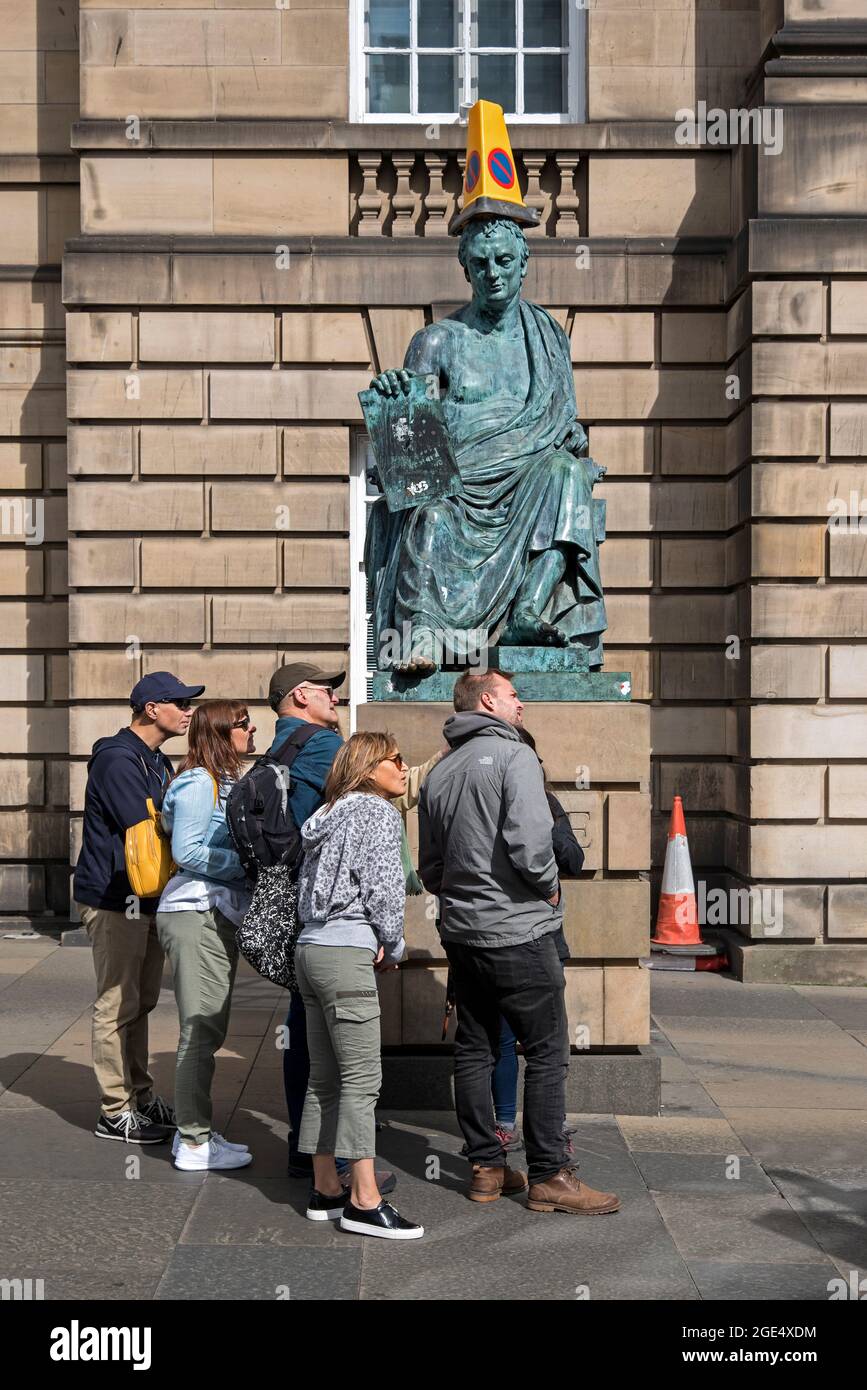 Statue of David Hume, with traffic cone, and tourists looking down the Royal Mile, Edinburgh, Scotland, UK. Stock Photo