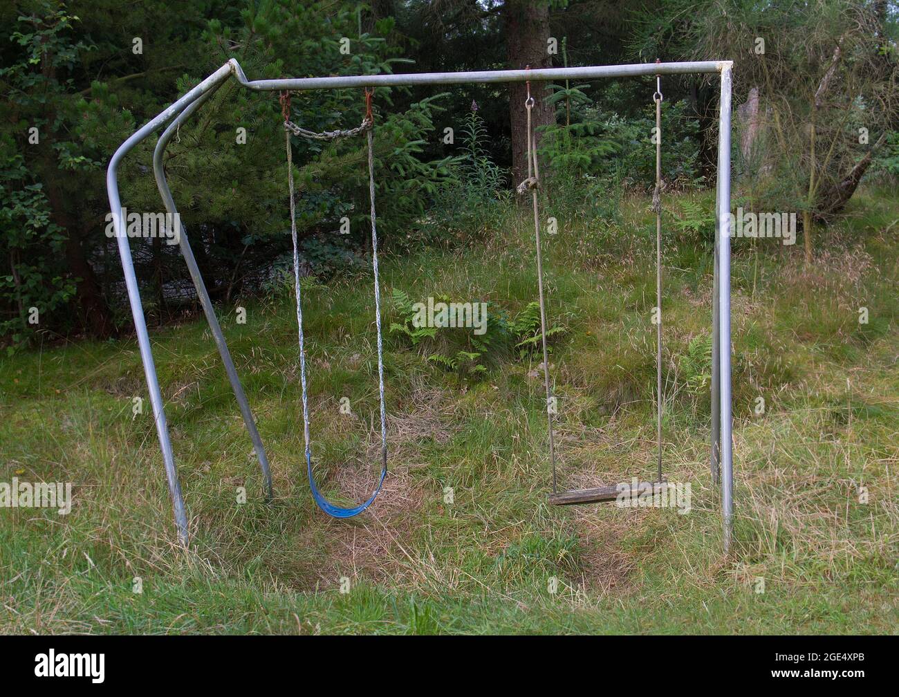Old, neglected, crooked swing, not used for a long time Stock Photo