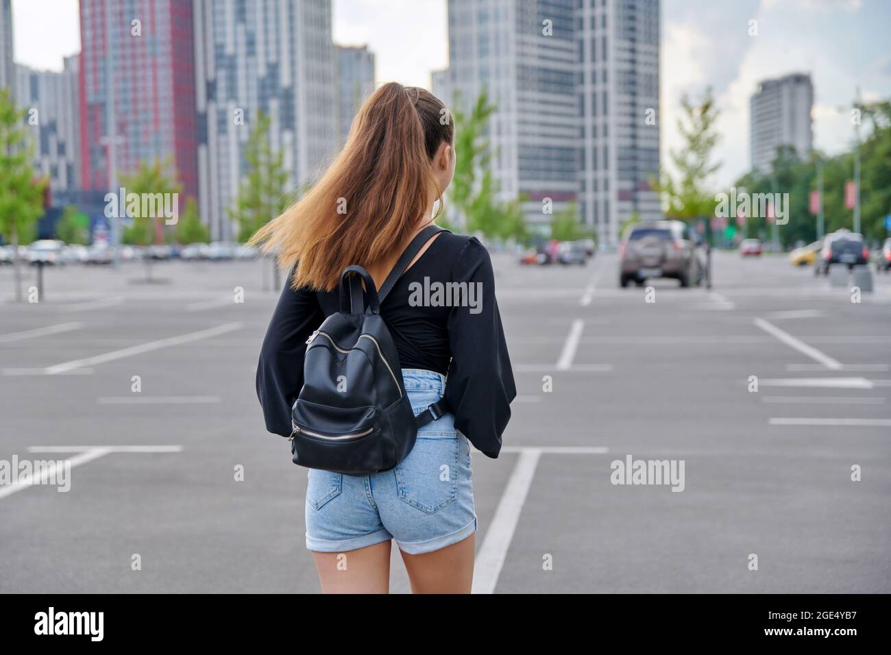 Back view of walking fashionable teenage girl with backpack Stock Photo ...