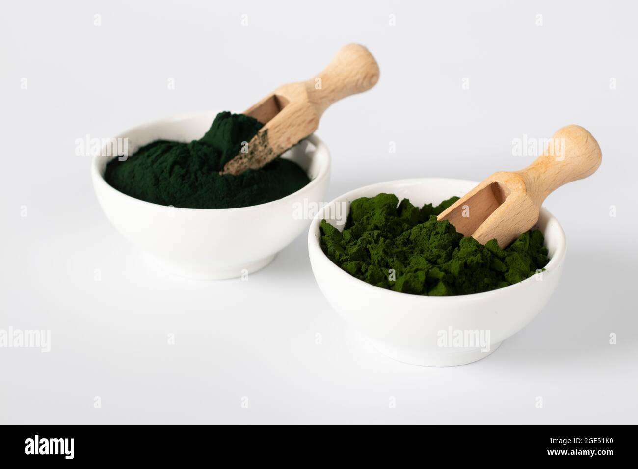 Organic algae chlorella and spirulina in powder form in white bowls