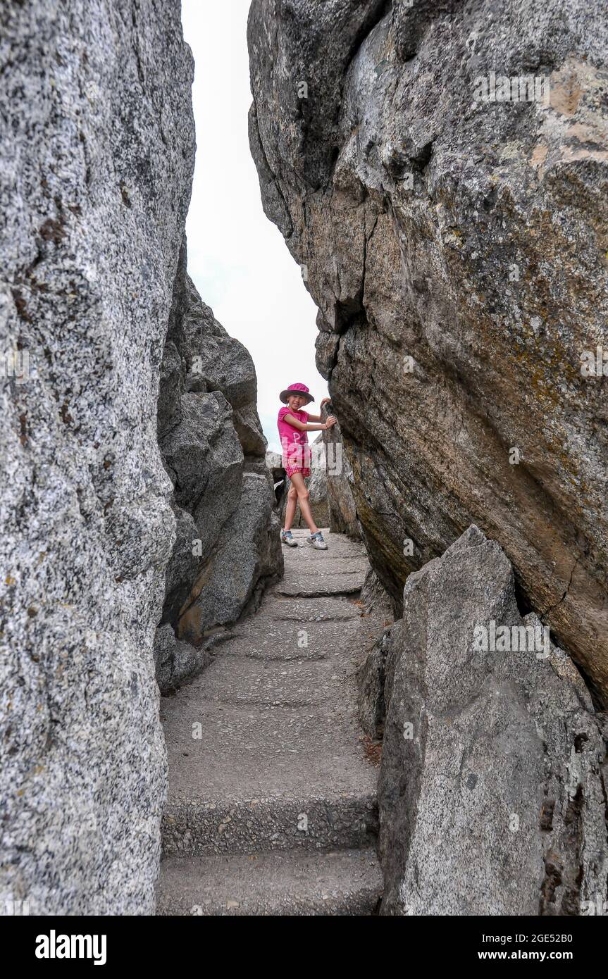 Young girl poses in narrow space between rock faces on Moro Rock Trail, Sequoia National Park. Stock Photo