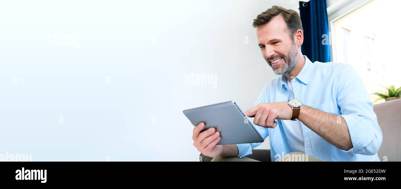 Handsome businessman working from home. Using app on tablet to telecommuting or sales reporting Stock Photo