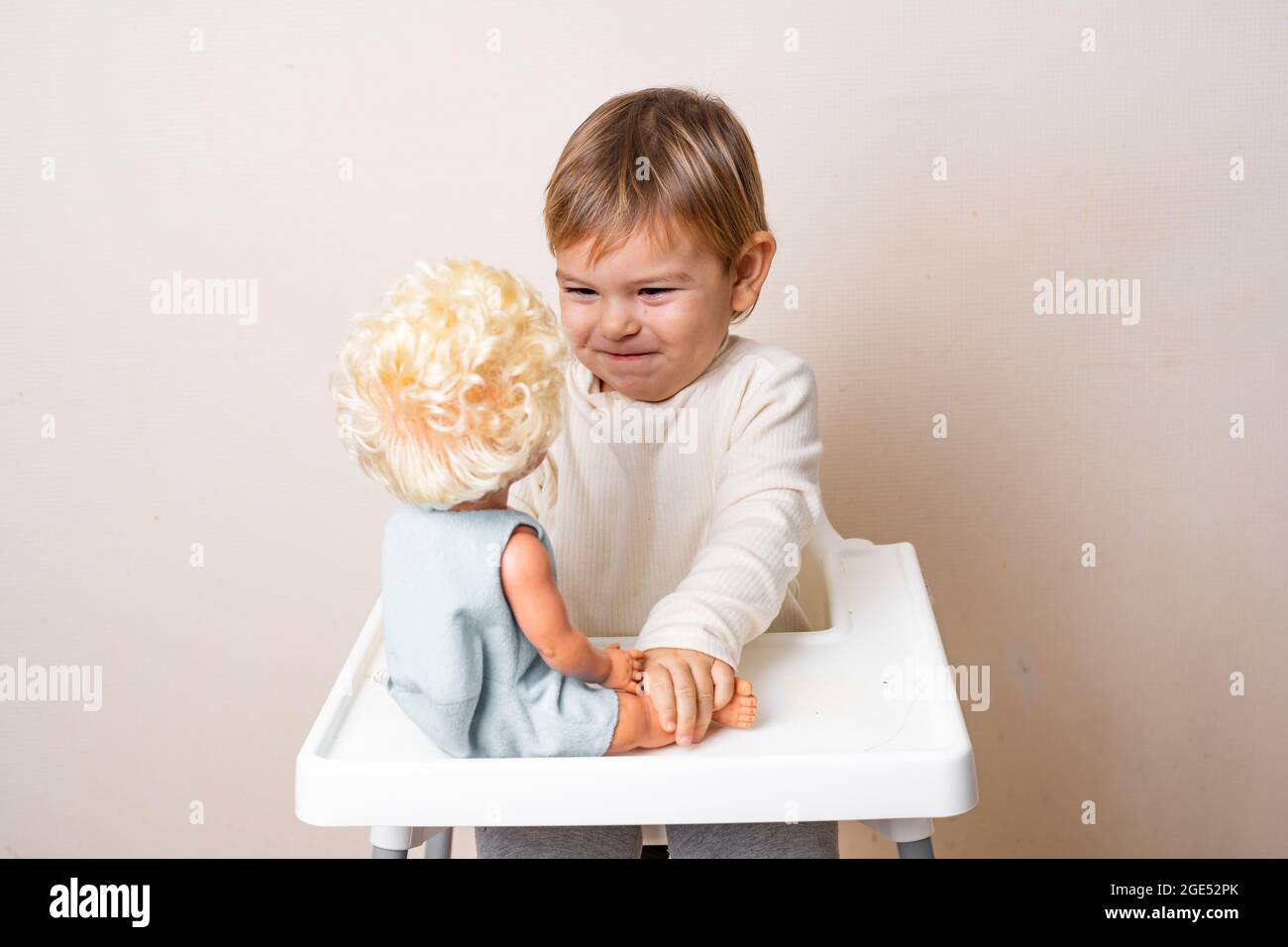 Baby toddler plays with old-fashioned doll on a studio shot. Funny ...