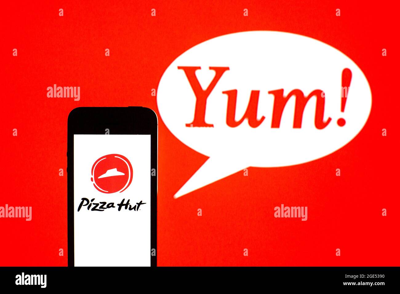 In this photo illustration, a Pizza Hut logo seen displayed on a smartphone with a Yum! Brands logo in the background. Stock Photo