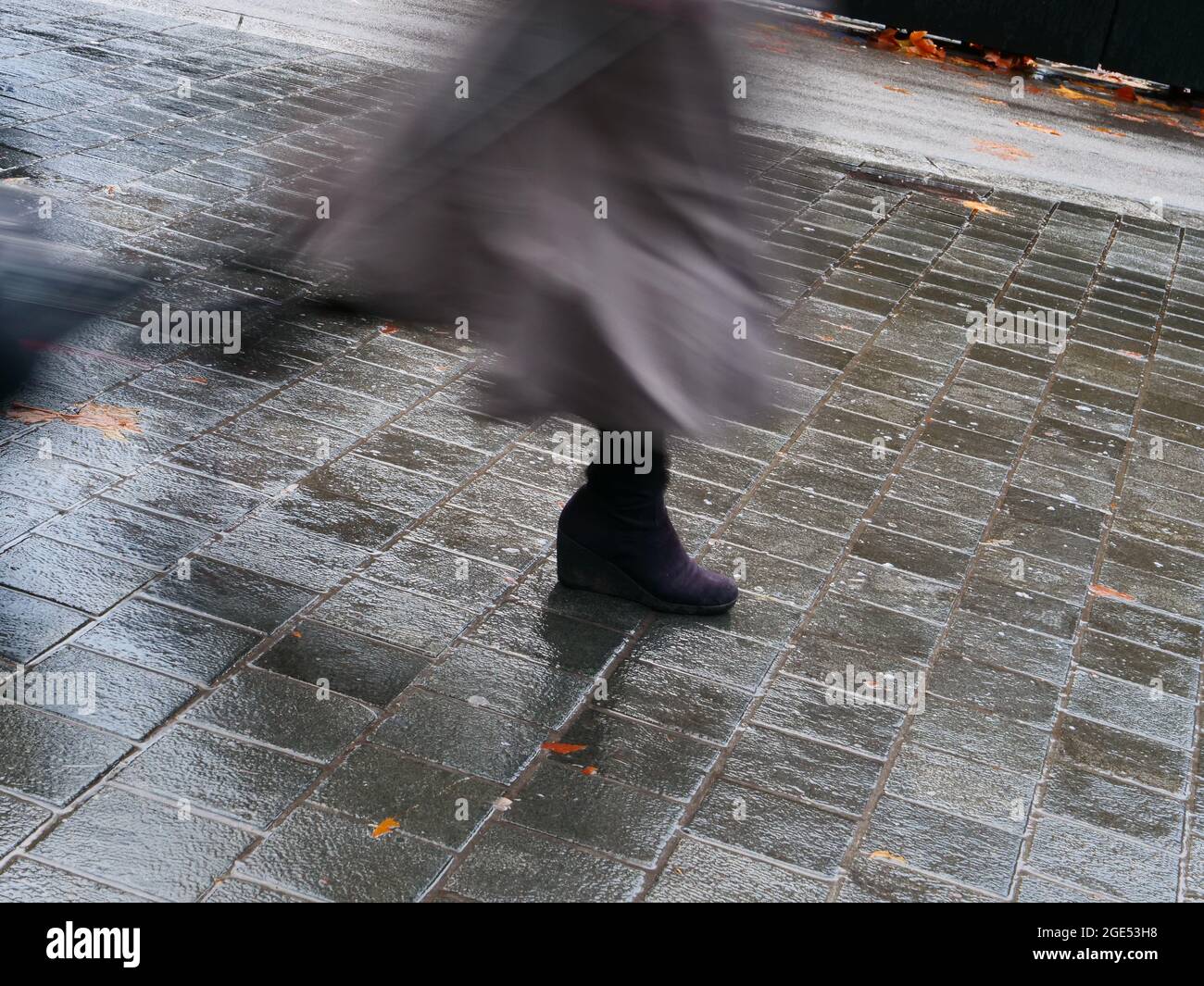 Person seen fast walking in a rainy street. Stock Photo